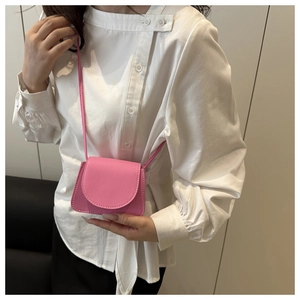 Detail of fuchsia lychee leather mini crossbody bag with fine stitching and flap closure
