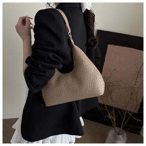 Side view of khaki crocodile embossed shoulder bag on a model in a black blazer