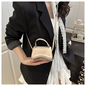 Mini borsa crema con base curva e manici in metallo indossata da una modella