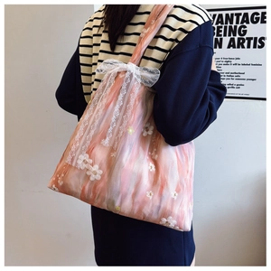 Detail of embroidered gauze tote bag with watercolor floral print and lace bow decoration