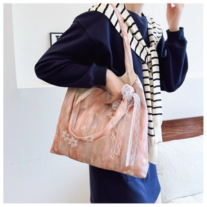 Dettaglio del ricamo floreale rosa e del fiocco in pizzo bianco sulla borsa tote chic