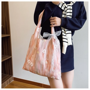 Dettaglio della borsa tote in organza rosa con ricami floreali e fiocco in pizzo