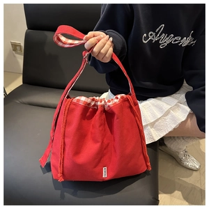 Detailed close-up of red canvas drawstring tote bag with red and white gingham lining details