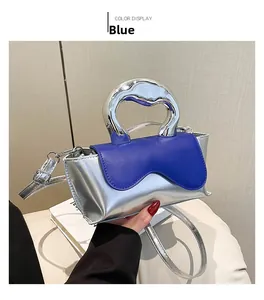 Detail of silver metallic PU handbag with a vibrant blue wavy flap and unique metal handle