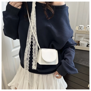 Detailed shot of white lacy strap on a minimalist faux leather crossbody square bag