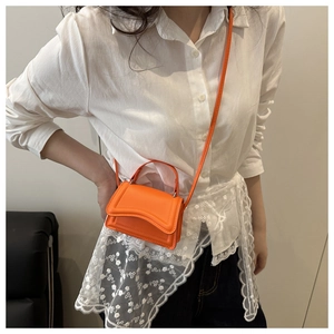 Dettaglio di mini borsa arancione vivace con chiusura a patta e tracolla regolabile