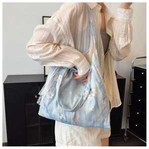 Dettaglio di una grande borsa tote con motivi acquerello azzurro e finiture in pizzo