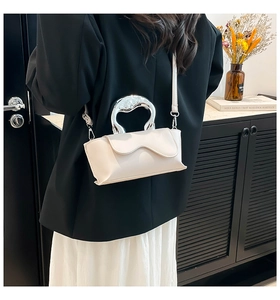 Close-up of cream-white bag featuring a unique silver metallic curved handle design