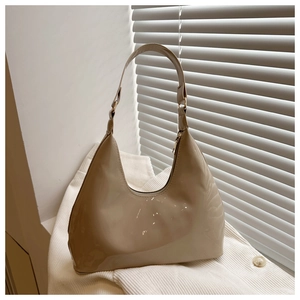 Detailopname van beige laks leren halve maan tas op wit corduroy met lichtinval