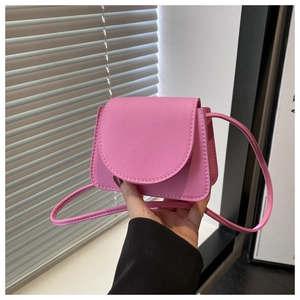 Close-up of pink mini crossbody bag in lychee texture PU leather held by hand