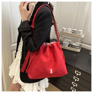 Detail of red canvas bucket bag with checkered drawstring and branded fashion patch