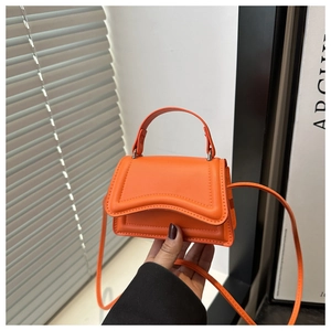 Dettaglio ravvicinato di una mini borsa arancione vivace in pelle martellata con manico