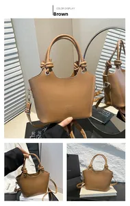 Detail of a brown bucket bag with knotted handle and embossed fashion logo lettering