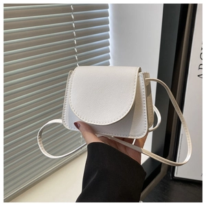 Detail of white mini crossbody bag featuring soft pebble leather texture and flap design