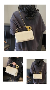 Détail du sac crème avec poignée dorée en forme de trombone et bandoulière en chaîne