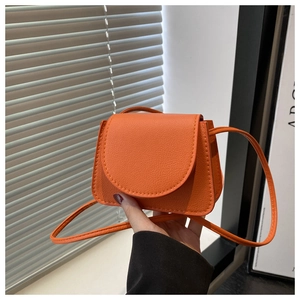 Detail of orange mini crossbody bag featuring premium lychee pattern faux leather texture