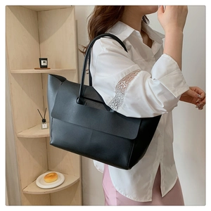 Lifestyle view of a spacious black leather tote bag worn by a model in a warm setting
