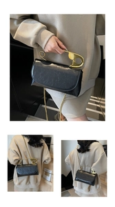 Détail d'un sac à main créatif en cuir verni noir avec une grande poignée épingle dorée