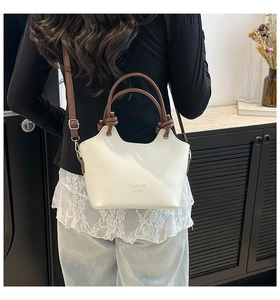Detail of white leather bucket bag with brown handles and Fashion H.C Bag lettering