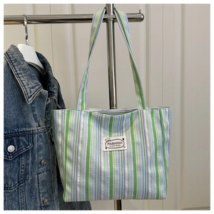 Close-up of green and purple striped canvas tote with Fashion original design label