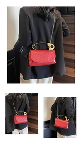 Détail d'un sac à main rouge brillant avec poignée créative en épingle à nourrice dorée