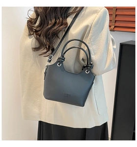 Close-up of stylish knot design and double ring handles on a black leather handbag