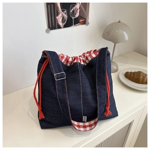 Detail of denim crossbody bag showing red checkered lining and adjustable shoulder strap