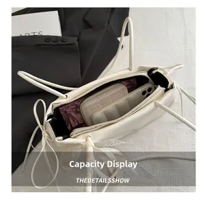 Vue de dessus d'un sac cabas crème en similicuir montrant l'intérieur spacieux et un nœud