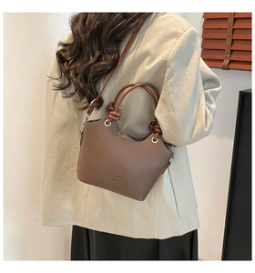 Detail view of the brown leather texture and elegant metallic ring eyelet on the handbag