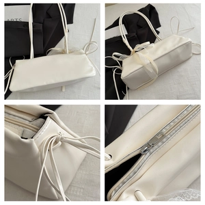 Détails du sac baguette crème montrant les lacets latéraux et la fermeture éclair argentée