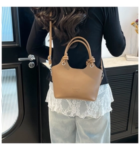 Brown leather bucket bag with tied handle detail shown in a lifestyle indoor setting
