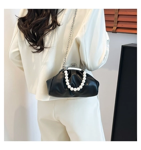 Detail of black pleated cloud bag with elegant pearl handle and metallic silver chain strap