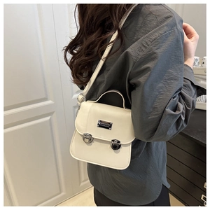 Detail of the white crossbody bag featuring silver push-lock buckles and handle