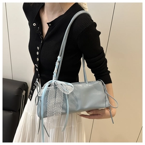 Detail of light blue baguette bag featuring delicate white lace bows and side drawstrings