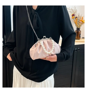 Detail of pink pleated clutch bag with large pearl handle and metallic chain strap