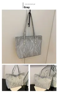 Dettaglio della borsa tote argento con finitura strutturata e rivetti dorati sui manici