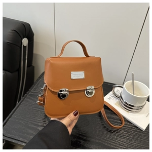 Détail d'un sac à main en similicuir marron caramel avec boucles argentées sur table