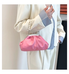 Detail of pink dumpling bag featuring pearl handle chain and soft pleated PU leather finish