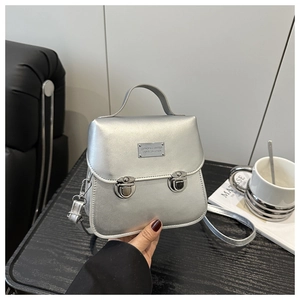 Détail du sac carré en cuir argenté avec double fermoirs et plaque en métal mode
