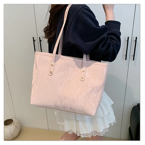 Detail of light pink tote bag with textured crinkle finish and gold rivet accents
