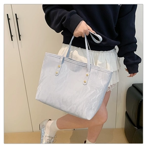 Detail of light blue tote bag with marble texture and elegant gold metallic rivets