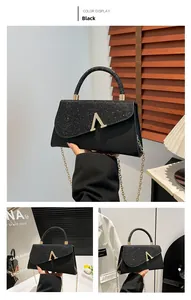 Detail view of black evening bag with sequined flap and golden V-shaped magnetic closure