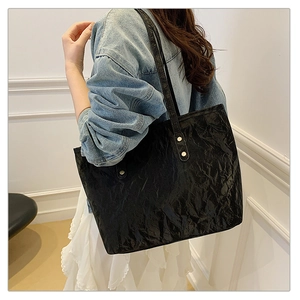 Detailed view of black tote bag with crinkled texture on shoulder of denim jacket