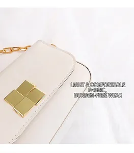 Detail of minimalist cream leather handbag featuring a square gold metal clasp and chain