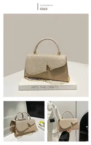 Close-up of champagne gold evening bag with V-shaped metal clasp and rhinestone texture