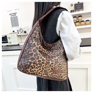 Close-up of leopard print tote bag featuring brown leather straps and spacious design