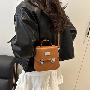 Model wearing a vintage brown leather bucket bag with silver buckles and flap closure
