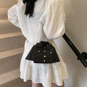 Creative black leather jacket shaped crossbody bag with silver chain strap on white dress