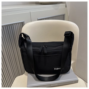 Detail of the black nylon crossbody bag featuring a fashion label and dual zippers