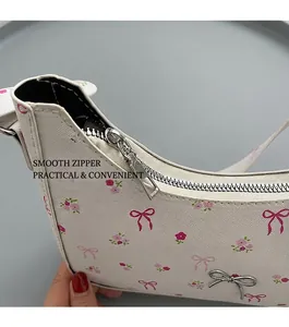 Detail of smooth metal zipper and cute bow charm on white floral shoulder bag